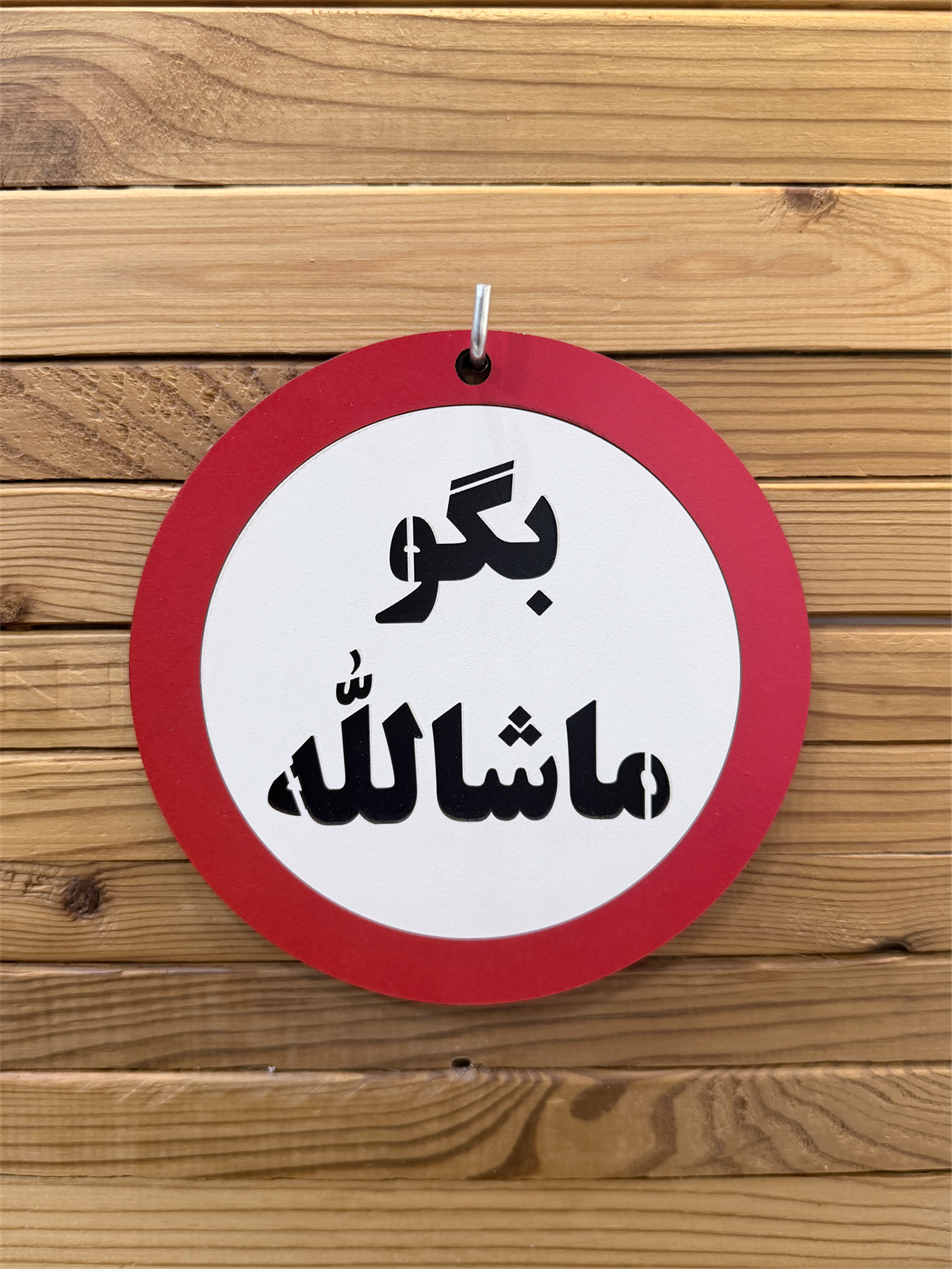 تابلو چوبی بگو ماشالله نصب شده روی دیوار چوبی