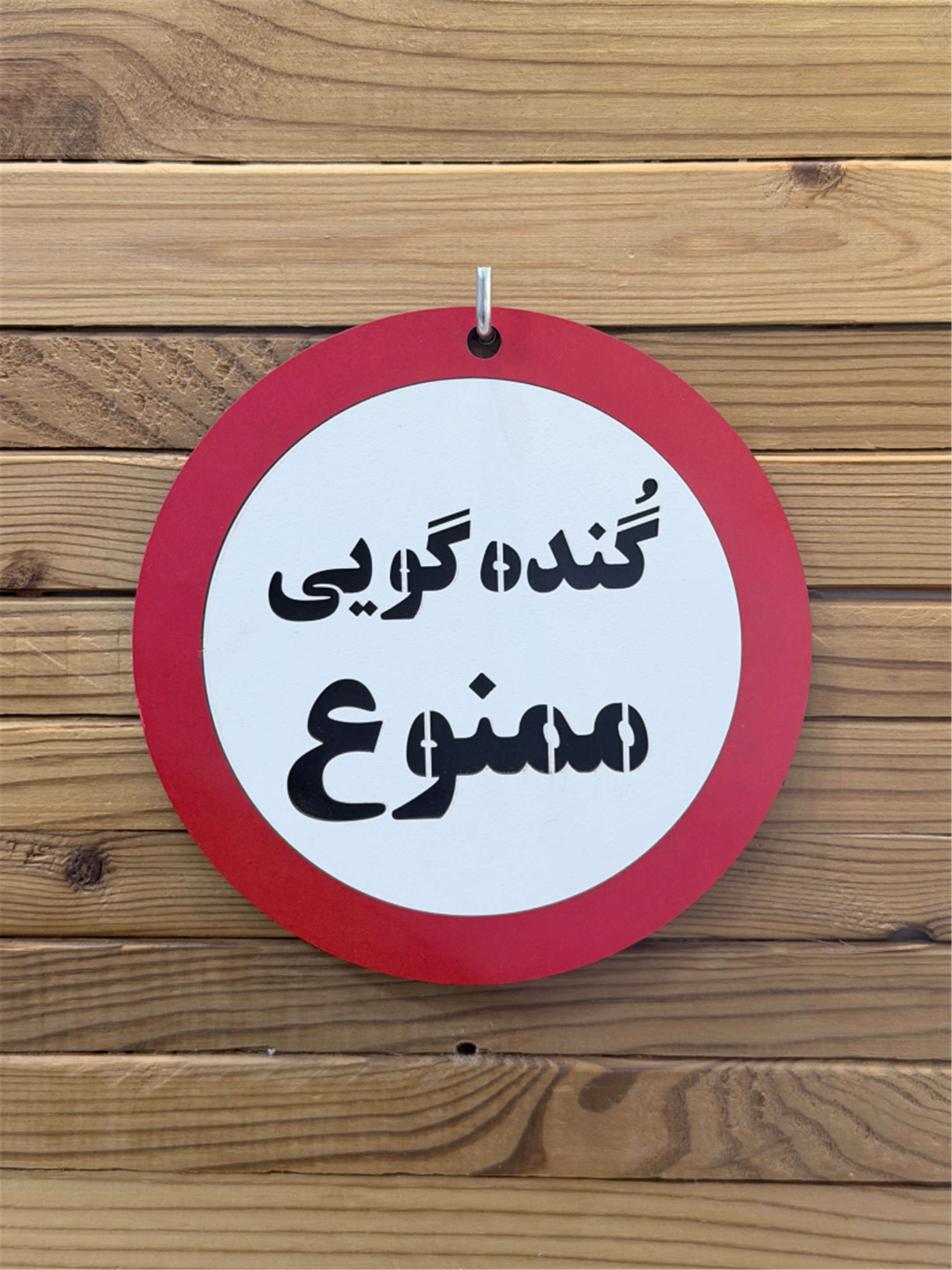 تابلو چوبی گنده گویی ممنوع با حاشیه قرمز روی دیوار چوبی