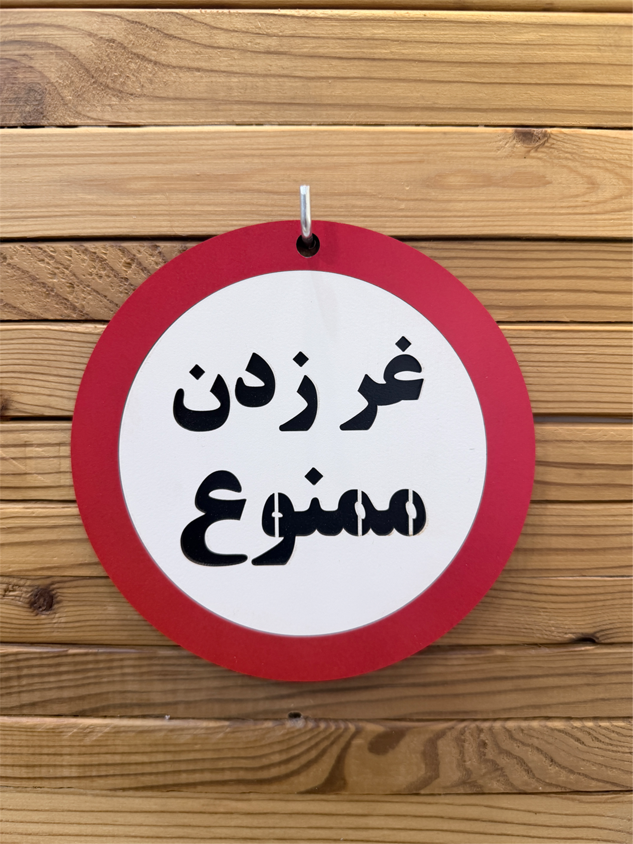 تابلو چوبی غر زدن ممنوع نصب شده روی دیوار چوبی اتاق