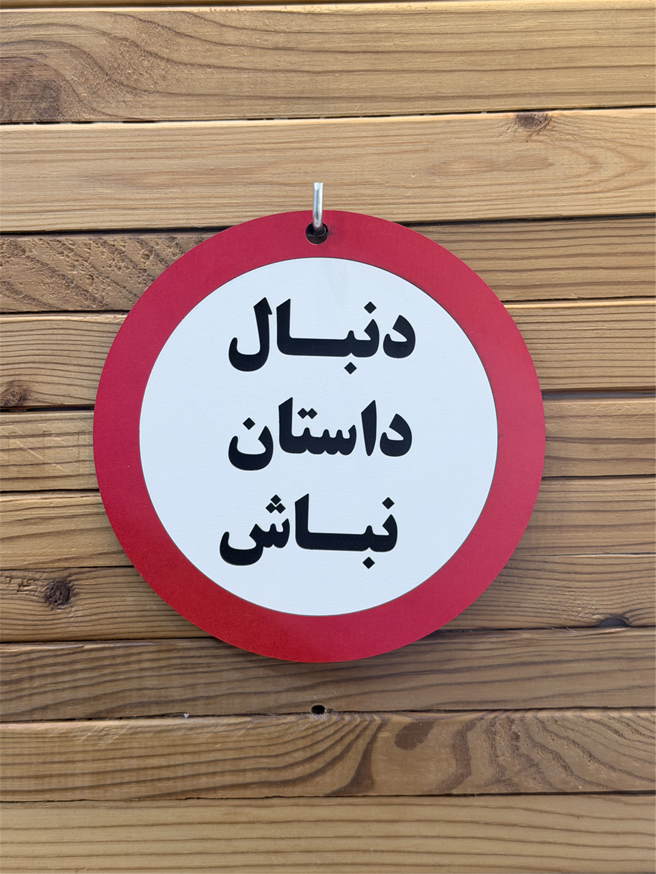 نمای روبرو تابلو چوبی دنبال داستان نباش با حاشیه قرمز